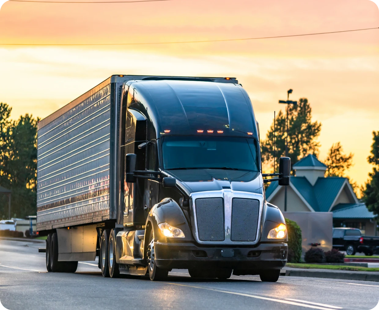 Black semi-truck driving at sunset